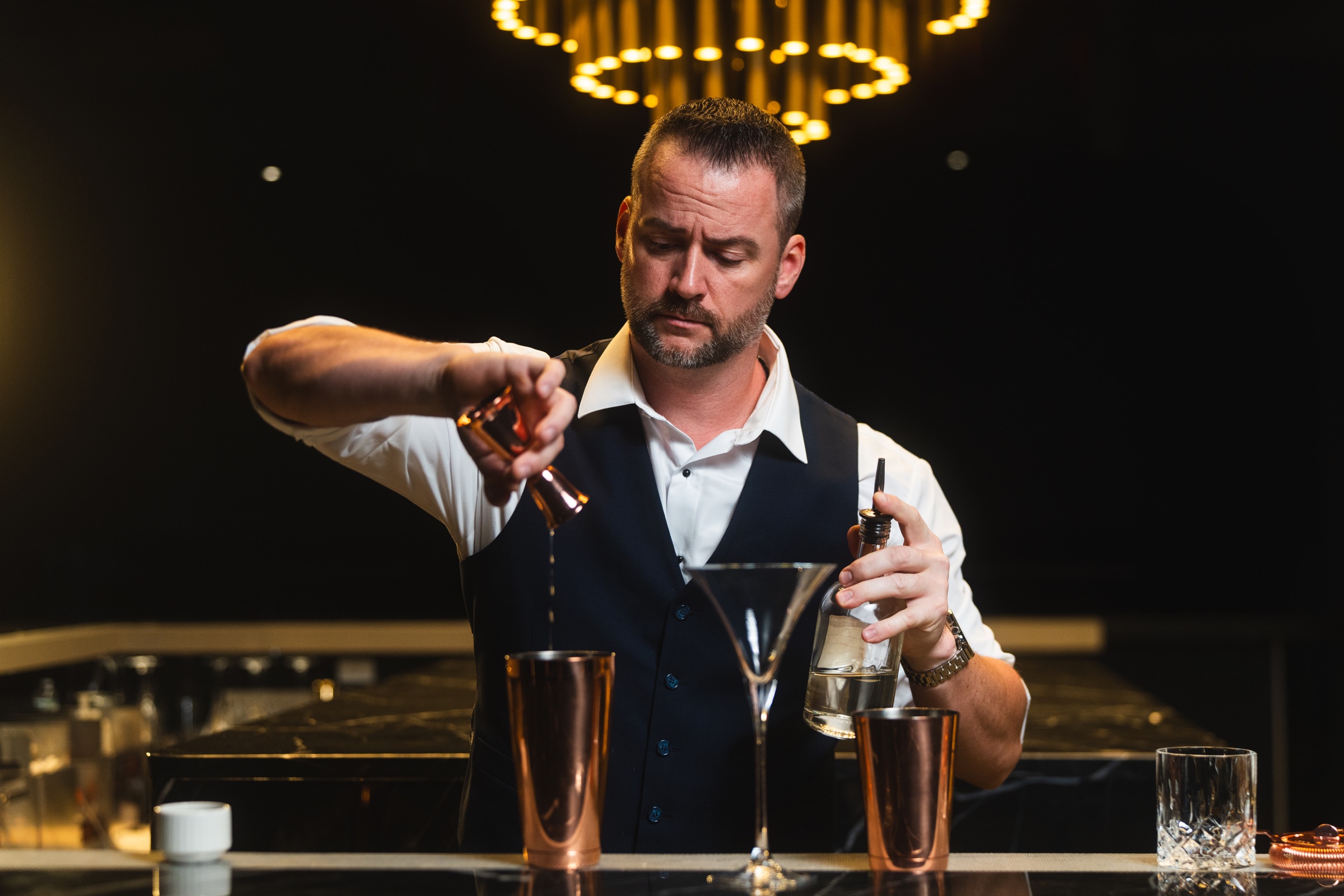 Bartender at work beneath the warm lights of a cocktail bar