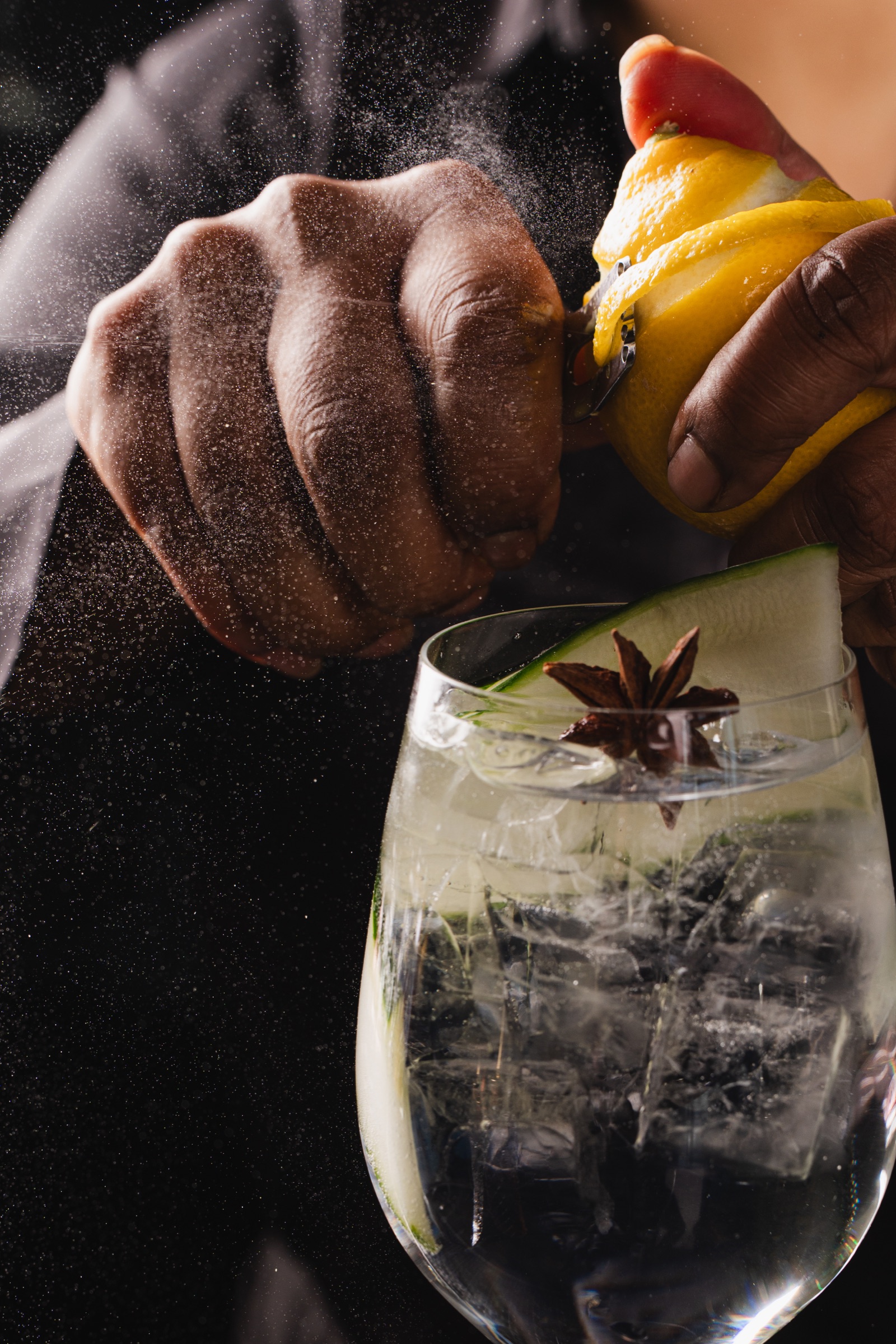 Close view of a bartender expressing fresh citrus over a finished cocktail